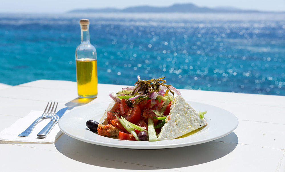Prato da gastronomia grega com diversos vegetais, com vista para o Mar Mediterrâneo
